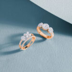 Rose gold diamond rings displayed on a textured blue surface