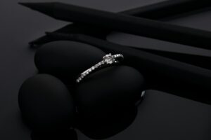 Diamond ring on black stone surface with dramatic shadows.