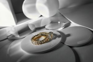 Gold diamond rings on white pedestal with soft shadows.