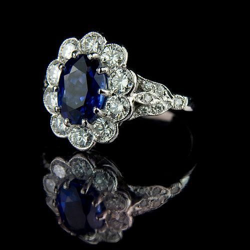 Blue sapphire diamond halo ring on black reflective surface