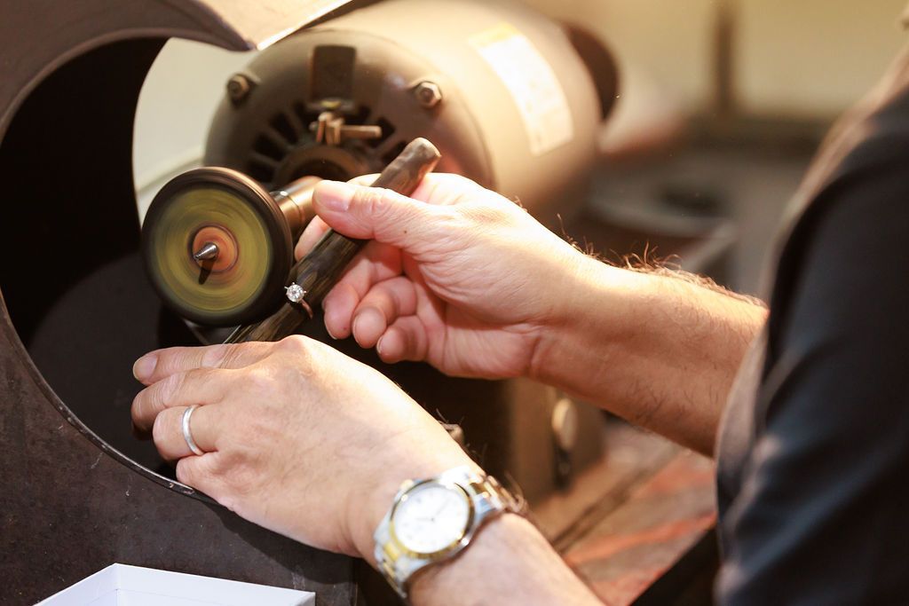 Jeweler polishing diamond ring on a buffing wheel