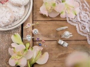 Wedding rings and jewelry arranged with flowers on wood