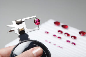 Gemologist inspecting a red gemstone with precision calipers